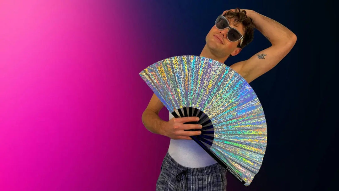 Man holding a silver metallic clack fan at a circuit party