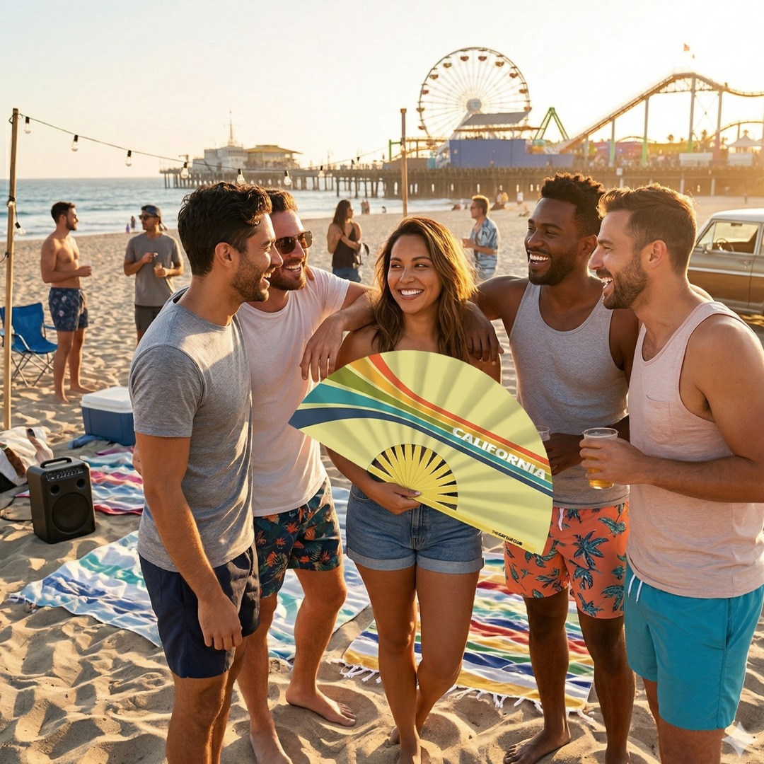 Group of friends holding the "California Clack Fan" on a beach with a Ferris wheel and pier in the background