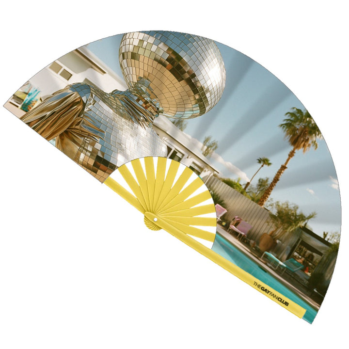 Disco Diva Fan fully open showing a surreal figure with a disco ball head in a silver suit lounging by a Palm Springs pool, set against yellow bamboo ribs