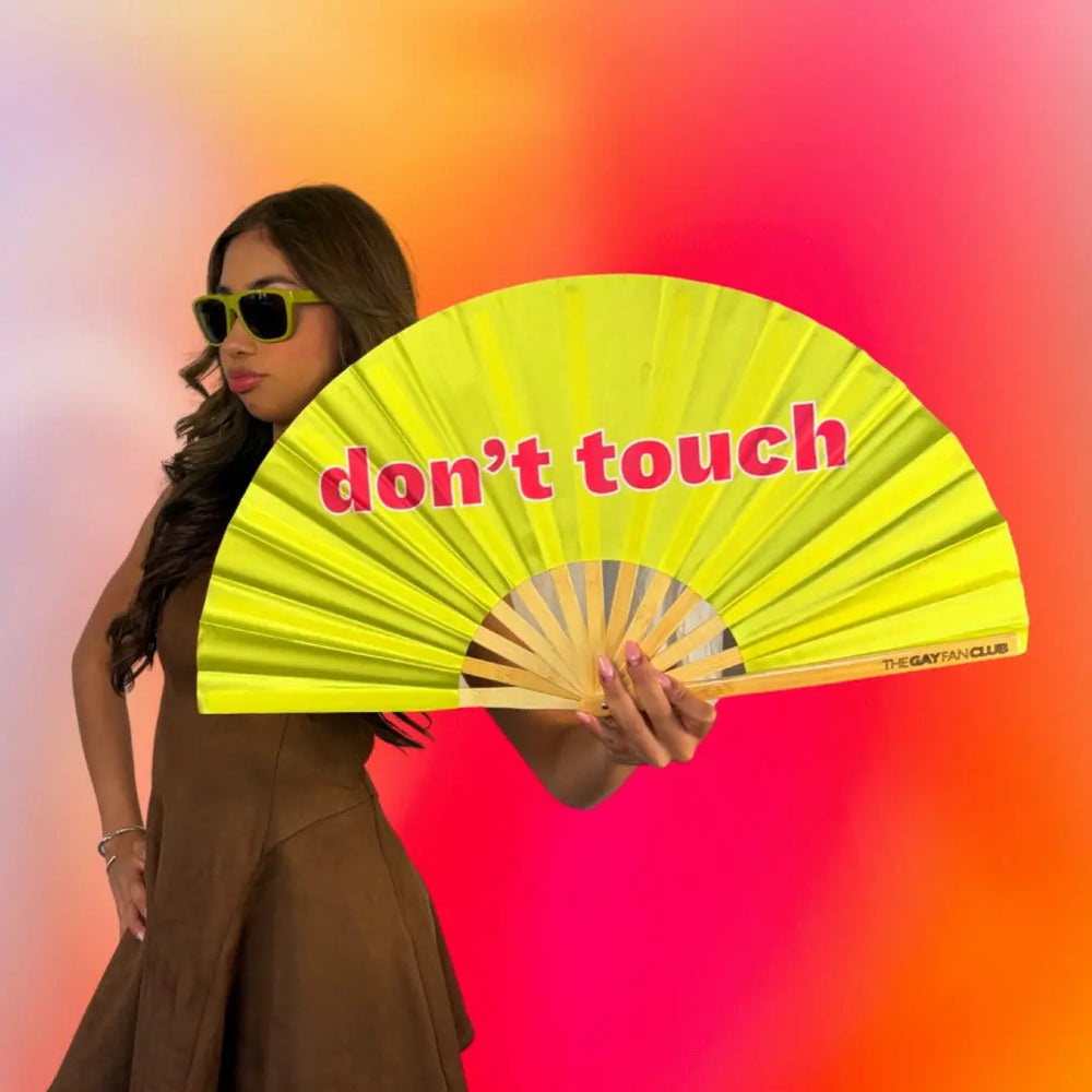 woman holding a neon yellow bamboo clack fan with the words Don't Touch in red