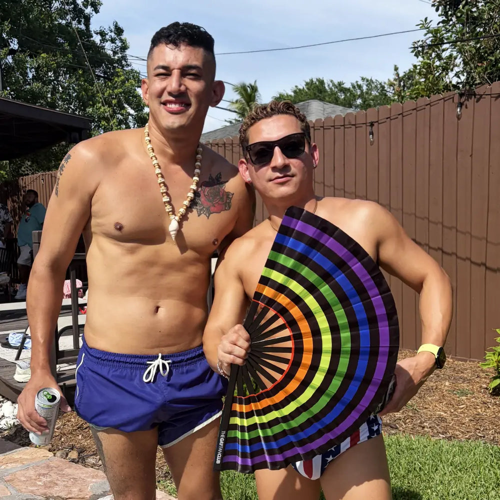 two attractive gay men holding a black electric rainbow clack fan at the Gay fan Club