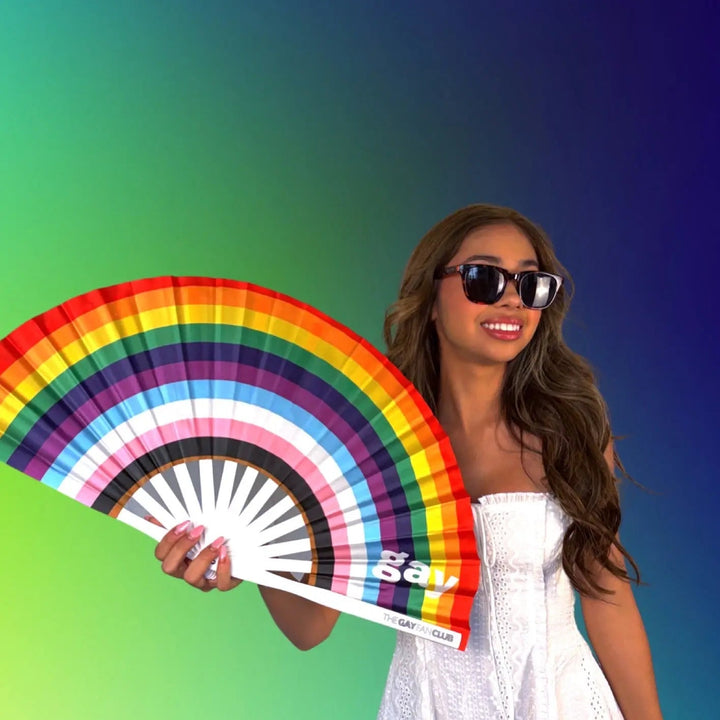 Woman holding a rainbow-colored fan against a gradient background