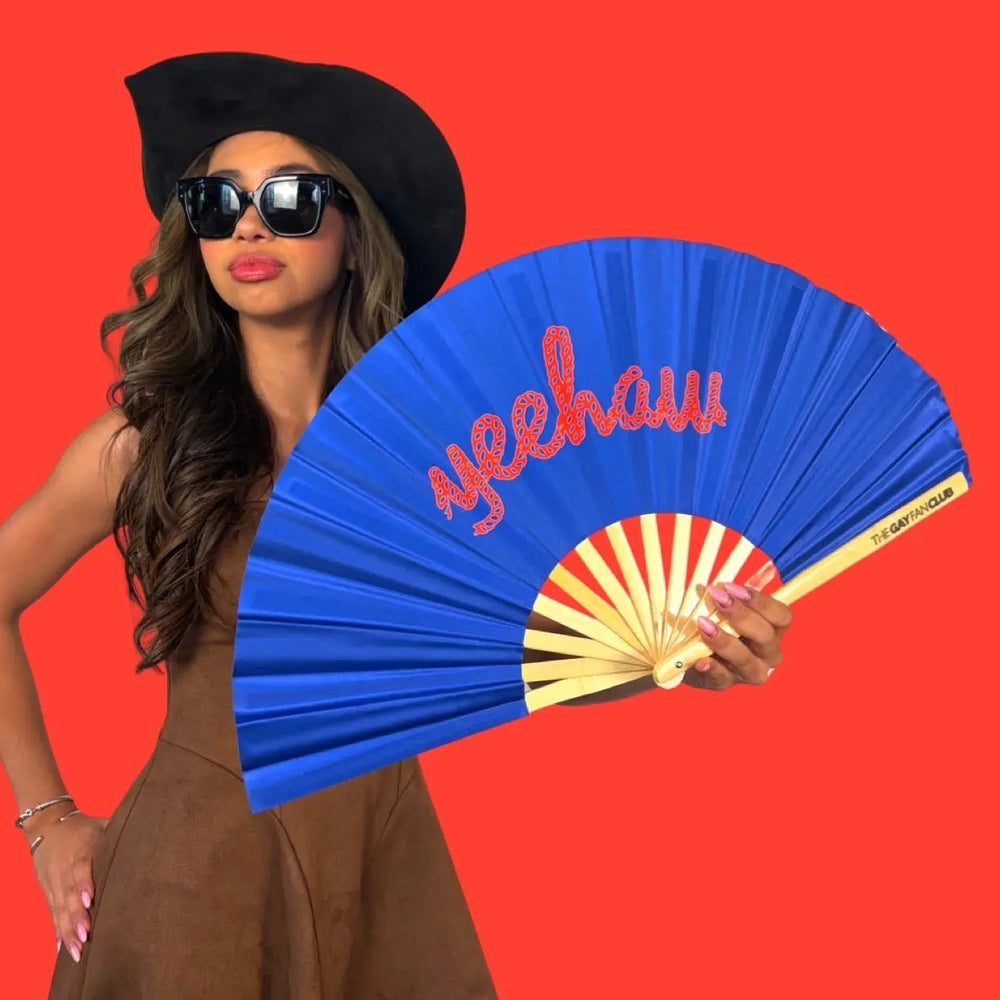 Woman holding a blue fan with 'Yeehaw' text against a red background