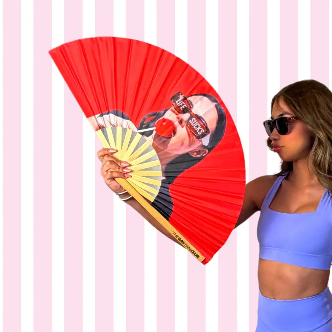 Woman holding a red and yellow fan with a graphic design against a pink striped background