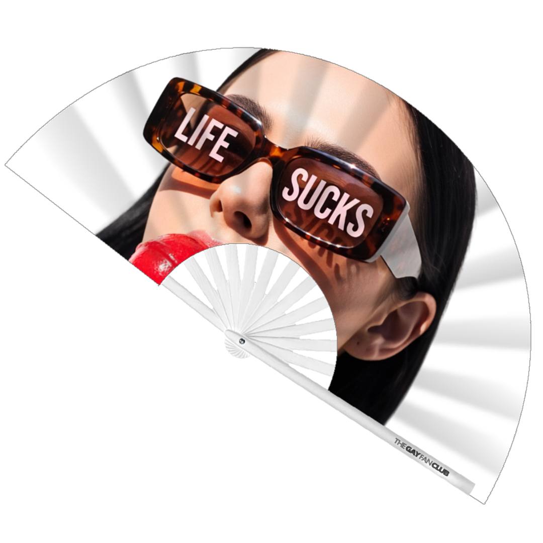 Life Sucks Fan fully open showing a woman in tortoise-shell sunglasses with "LIFE SUCKS" text on the lenses, holding a red lollipop, set against white bamboo ribs.