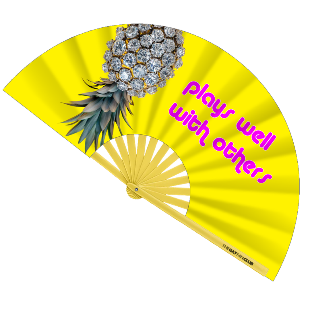 Pineapple Play "Plays Well With Others" Fan fully open showing a bright yellow background with a diamond-studded upside-down pineapple and neon purple text on a yellow bamboo frame.