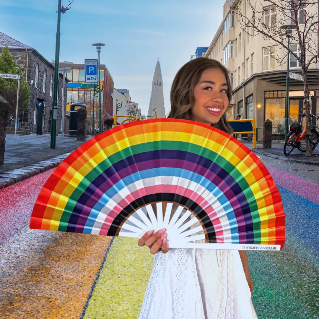Woman holding a rainbow-colored fan on a city street